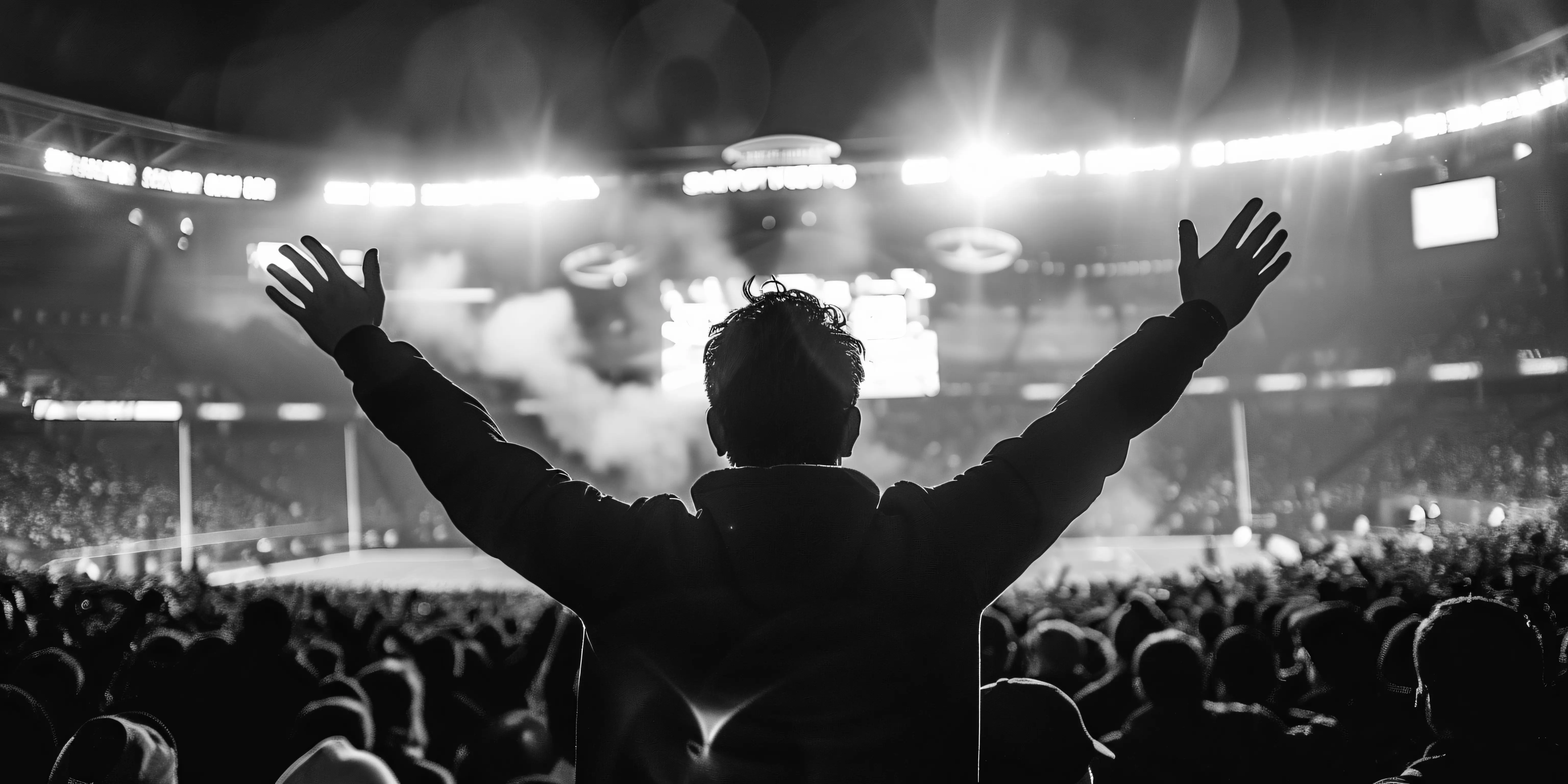 Persona con los brazos levantados frente a un escenario de concierto